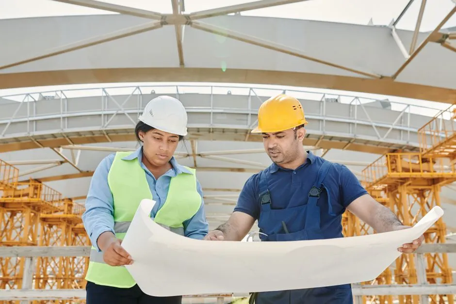 Deux ouvriers en casque qui consultent un plan sur un chantier